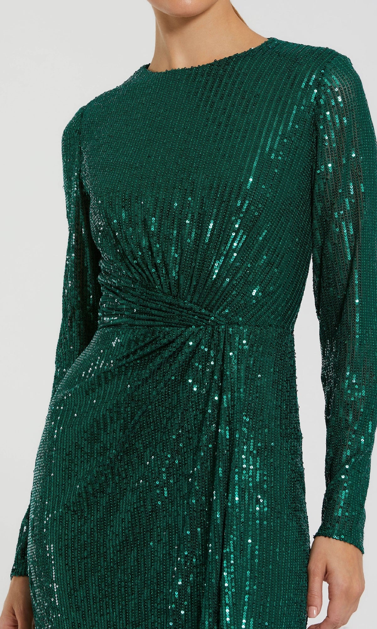 A person wearing the Mac Duggal 11659 long sleeve sequin formal dress in emerald green, featuring a gathered twist detail at the waist.